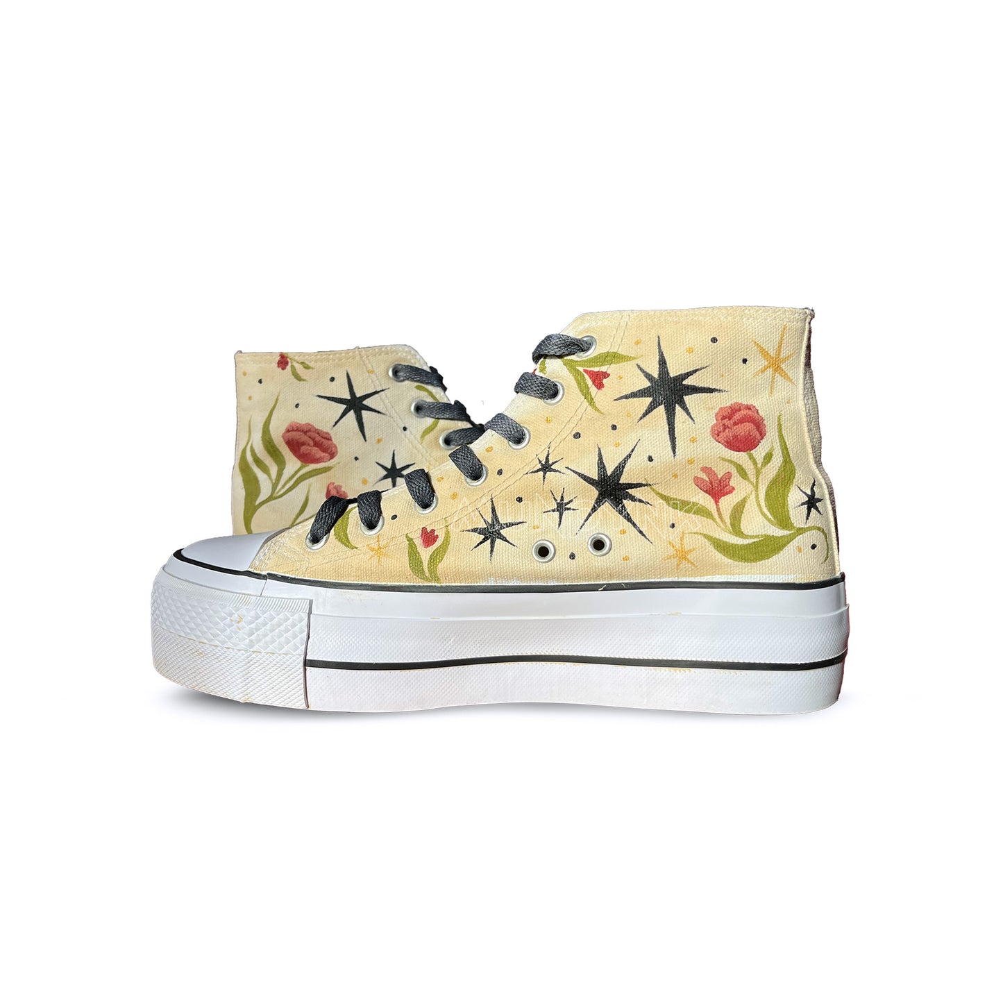 zapatillas pintadas de plataforma, con cordones negro, con patron de estrella negra, y flores con hojas roco y verde oliva