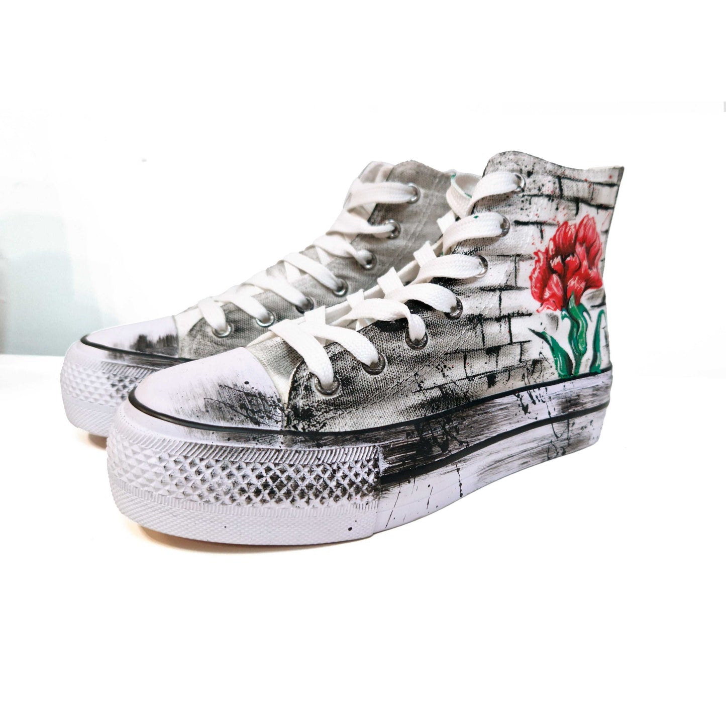 Zapatillas de tela pintadas a mano, de plataforma, con diseño de claveles rojos y la palabra "Madrid" en rojo. Fondo difuminado en gris con salpicaduras de pintura negra.